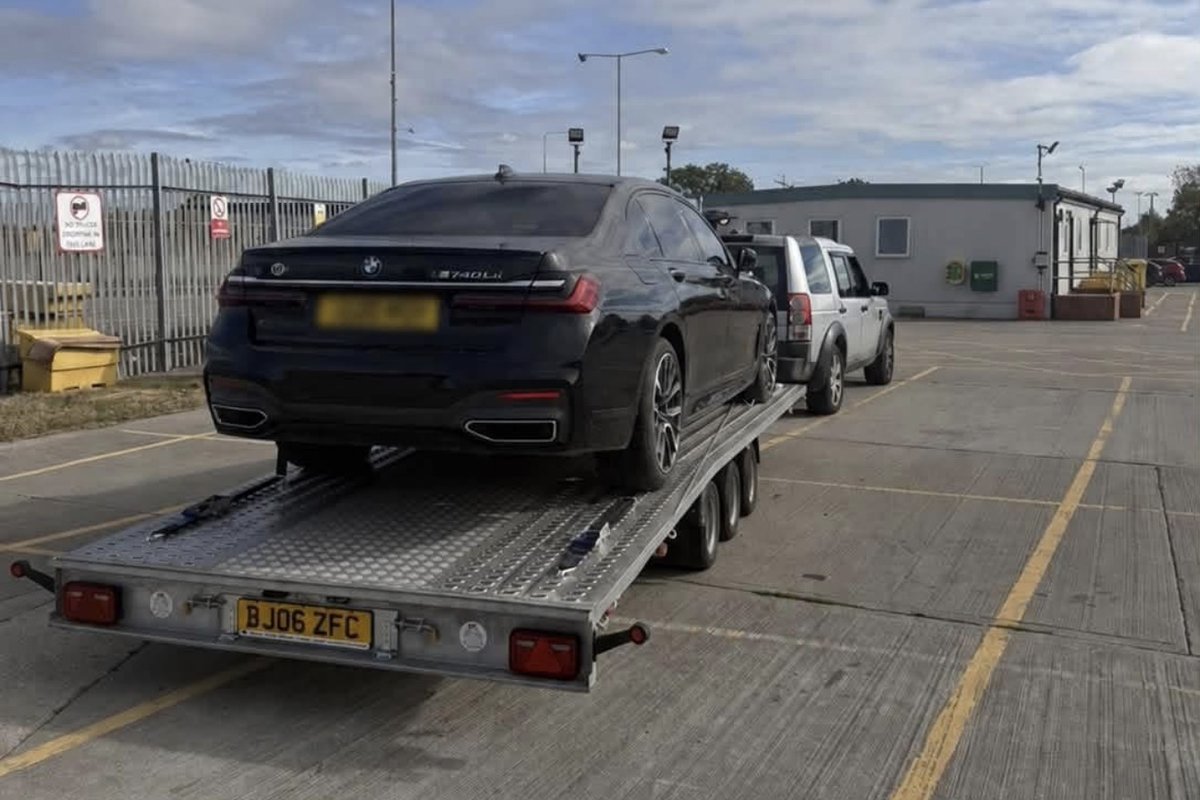 Black BMW 740Li loaded for transport on the tri-axle trailer