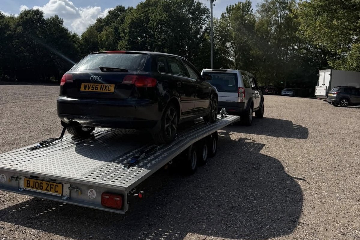 Black Audi A3 hatchback secured on the flatbed transporter trailer