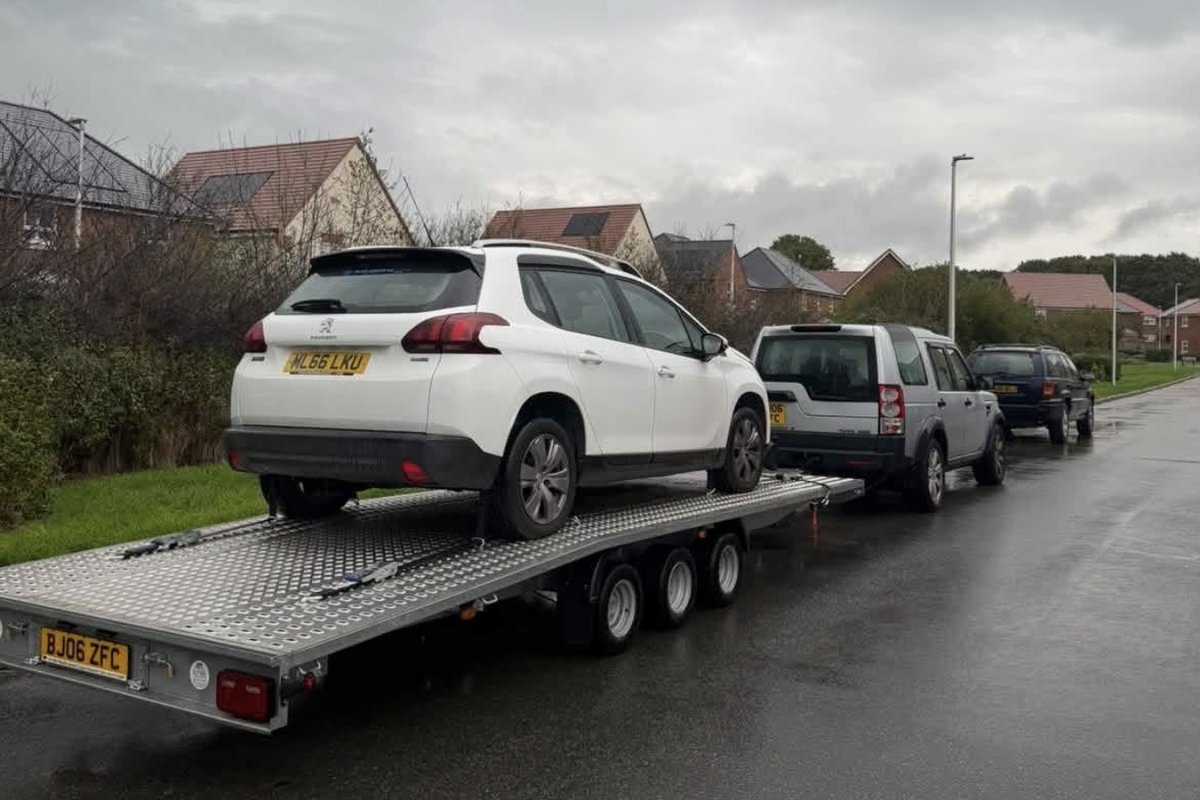 White Peugeot 2008 loaded on the tri-axle transporter trailer behind a Land Rover Discovery